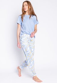 Lichtblauw T-shirt met korte mouwen, gecombineerd met losse, gestreepte pyjamabroek in blauw en geel met stippen. Zachte stof, met een koord in de taille.