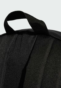 Černý batoh s texturovanou tkaninou, bočními záhyby a pevným tkaným madlem pro snadné nošení.