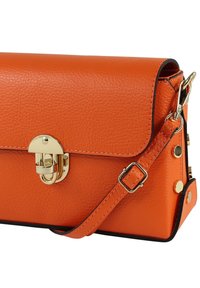 Oranje leren handtas met een gestructureerde afwerking, gouden sluiting, verstelbare riem en metalen accenten aan de zijkanten.