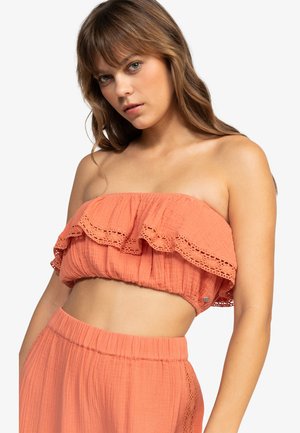Coral strapless top with a ruffled, lace-trimmed neckline; textured, lightweight fabric; elastic band at the bottom for fitted wear.