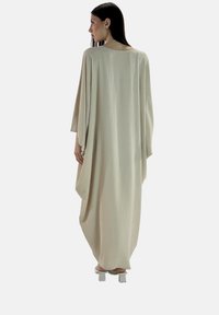 Beige, losse lange jurk met oversized mouwen, een soepele textuur en een gedrapeerd ontwerp, die een minimalistische esthetiek toont.