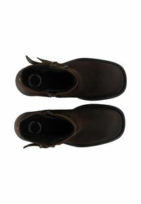 Botas de tobillo de cuero marrón con punta redondeada, correa lateral y hebilla decorativa de metal. Superficie texturada con detalles de costura.