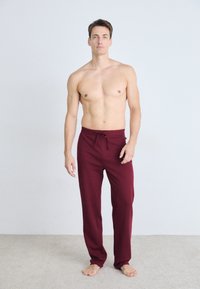 Bordeaux kleur, joggingsbroek met trekkoord. Gemaakt van zachte stof, met een ontspannen pasvorm en recht gesneden ontwerp. Geen patronen of zichtbare hardware.
