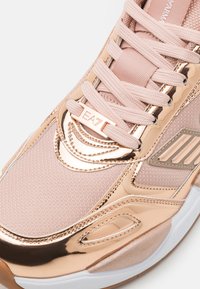 Jasnoróżowe sneakersy z metalicznymi różowo-złotymi akcentami, teksturowana siateczkowa cholewka, płaskie sznurowadła i detal z logo. Wzmocniony nos i wyściełany kołnierz.
