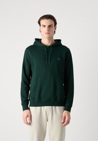 Felpa verde in cotone con tasca frontale, cappuccio con coulisse e una piccola etichetta logo. Il tessuto ha una texture liscia e una vestibilità comoda.