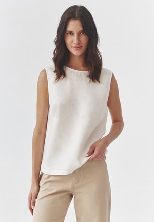 Lightweight, sleeveless linen top in off-white, featuring a round neckline and a relaxed fit, paired with beige pants. Smooth texture.