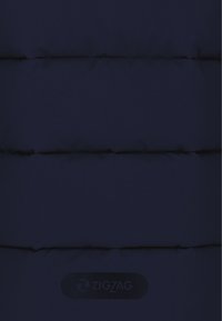 Marineblauer gepolsterter Stoff mit sichtbaren Nähten und weicher Textur; verfügt über ein auffälliges schwarzes "ZIGZAG"-Logopatch nahe dem Saum.