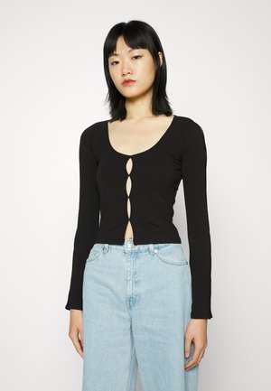 Top preto de manga longa com decote em forma de coração e detalhe de fecho com cinco botões na parte da frente. Tecido macio e elástico; design just fitted.