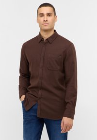 Braunes Langarm-Hemd mit Knopfleiste, Kragen und Tasche, aus weichem Stoff gefertigt. Verfügt über ein dezentes Logo auf der Tasche und einen abgerundeten Saum.
