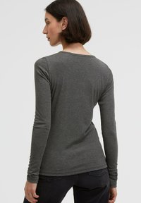 Long-sleeve gray shirt made of soft fabric; features a rounded neckline and fitted sleeves, displayed from a rear angle.