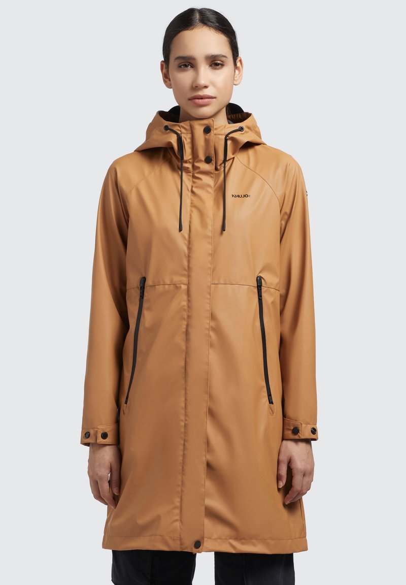 Wasserfeste braune Outdoorjacke mit Kapuze, schwarzen Reißverschlüssen, Akzentknöpfen und verstellbaren Zugbändern; knielanger Schnitt.