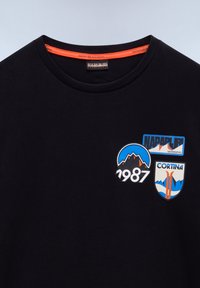 Sort bomulds T-shirt med rund hals, der har tre farverige mærker: "Napapijri," "Cortina," og et bjerggrafik med "1987."