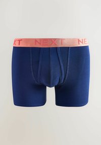 Sötétkék boxeralsó pink elasztikus derékkal, amelyen a "KÖVETKEZŐ" szó ismétlődik. Sima текстúra, funkcionális sliccel rendelkezik.