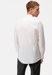 Weißes Langarmhemd mit klassischem Kragen, glatter Textur, subtiler Schimmer und knöpfbaren Manschetten; taillierte Passform betont einen strukturierten Look.
