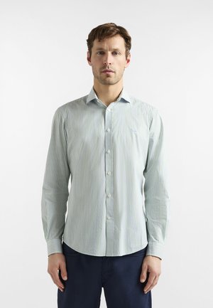 Lyseblå skjorte med knapper foran, lodrette striber i grøn og mørkere blå, lange ærmer og spids krave. Blød stoftekstur.