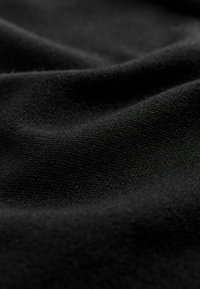 Schwarzer Stoff mit glatter Textur, verfügt über ein weiches, mattes Finish und dezente Variationen in den Oberflächenmustern und Falten.