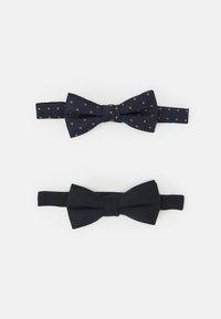 Dos pajaritas: una de color azul marino oscuro con lunares naranjas y otra de color azul marino oscuro sólido, ambas hechas de tejido texturizado con correas ajustables.