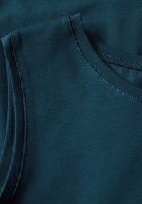 Tumman teal tank top -kangas, jossa on ribbikuvio ja pyöreä kaula-aukko sekä sileät tikkausläpiviennit reunoilla.