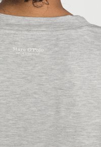 Szara bawełniana koszulka z okrągłym dekoltem i krótkimi rękawami. Na plecach znajduje się logo w białym kolorze z napisem "Marc O'Polo EST. W Sztokholmie."