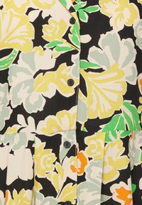 Vestido floral com fundo preto, grandes flores amarelas, verdes e laranjas, detalhes em botões e textura plissada.