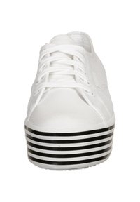 White canvas sneaker with a rounded toe, lace-up front, and a textured body. Features a black and white striped platform sole.