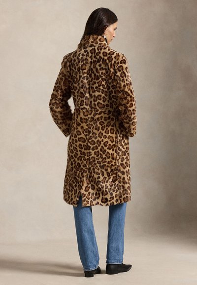 Kabát z umelej kožušiny s leopardím vzorom s golierom, strednou dĺžkou a bočnými rozparkami. Kombinovaný s modrými džínsami a čiernymi členkovými čižmami.