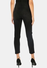 Czarne, wysokie skinny jeansy z postrzępionymi nogawkami, wykonane z denimu, z dwiema tylnymi kieszeniami i gładką teksturą.