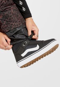 Sorte høj-top sneakers lavet af tekstil og gummi, med et hvidt bølgedesign, gummisål med grip og snørebåndslukning.