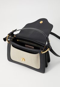 Sac à main en cuir noir avec une surface texturée, doté d'une poche avant en tissu beige et de quincaillerie dorée. Design structuré avec une poignée supérieure.