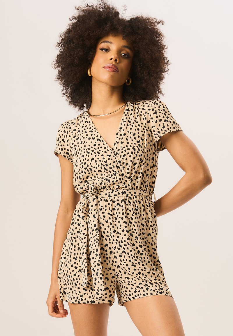 Beige wrap romper with short sleeves, black animal print, cinched waist, and tie belt. Soft fabric and relaxed fit for comfort.