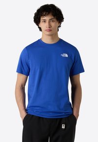 Blå bomulds t-shirt med korte ærmer, rund hals og et lille hvidt logo på brystet; glat tekstur, afslappet pasform.
