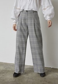 Gråternet bukser med høj talje, bred ben-design og knaplukning. Stoffet har en glat tekstur med kontrasterende hvide linjer.