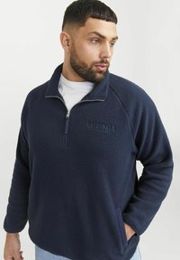 Mørkeblå fleece-pullover med halv-zip krave, struktureret overflade og sidelommer. Har broderet "ORIGINALS" på fronten.