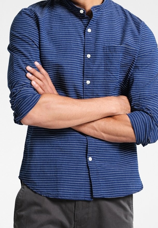 Marineblaue Button-Down-Bluse mit weißen Streifen, semi-casual Design und abgerundetem Saum; verfügt über eine Brusttasche und hochgerollte Ärmel.