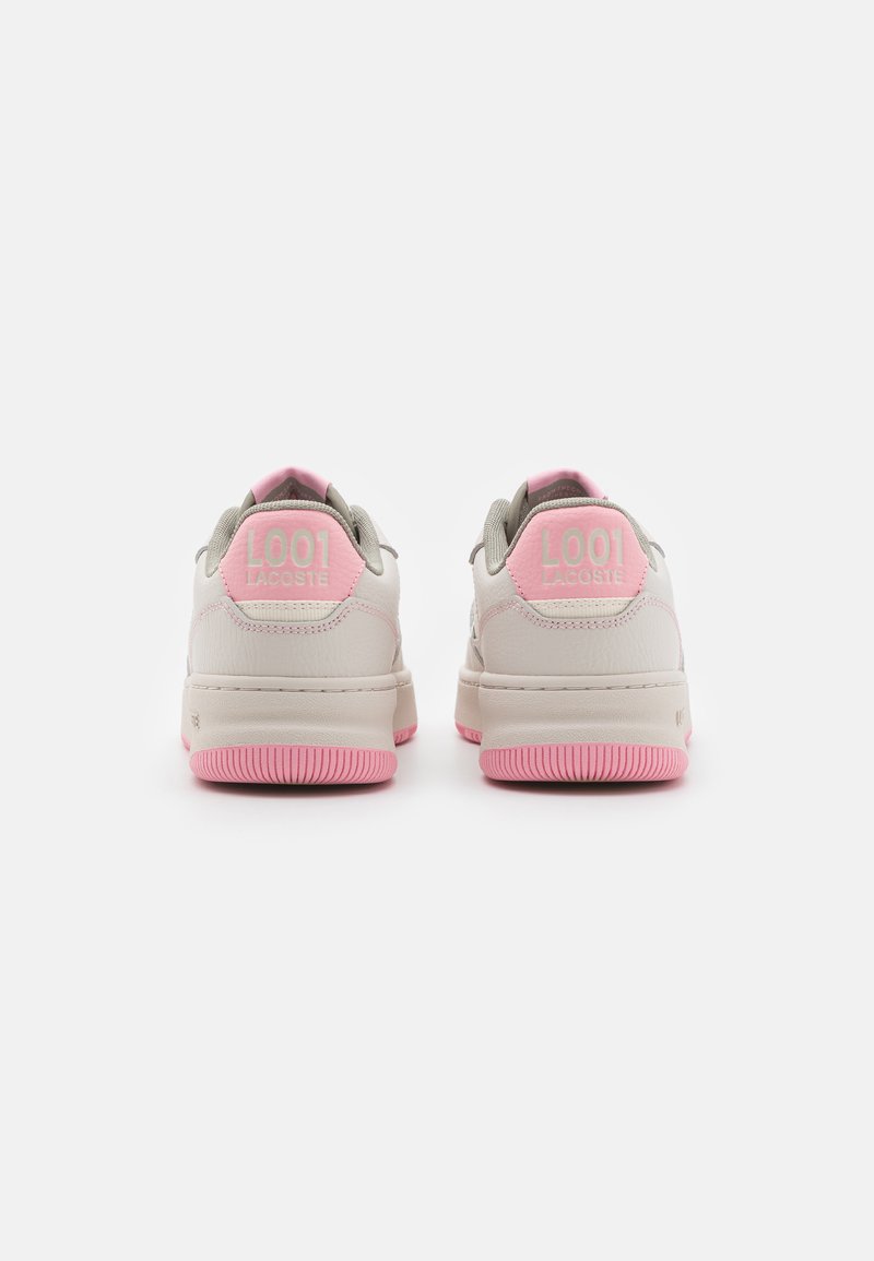 Baskets Lacoste avec un dessus en cuir beige, des accents gris et des détails de talon rose. La semelle en caoutchouc présente une texture antidérapante.