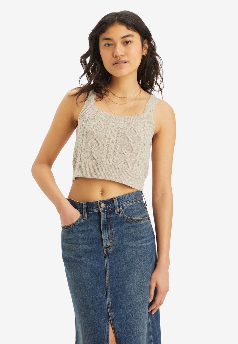 Top corto lavorato a maglia grigio chiaro con un motivo a treccia testurizzato e spalline larghe, abbinato a una gonna di jeans a vita alta con uno spacco anteriore.