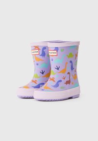 Bottes de pluie en caoutchouc violettes avec un motif de dinosaure en orange, vert et bleu. Présentent une semelle texturée et une étiquette de marque à l'avant.