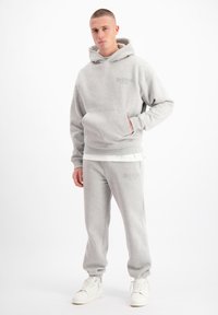 Grijze fleecetrui met een voorzak en geborduurd logo, gecombineerd met bijpassende joggingbroek met elastische boorden en logo-details.