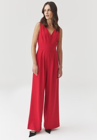 Rode mouwloze jumpsuit met een V-hals, een getailleerde taille en wijde broekspijpen. Gemaakt van soepele stof in een effen kleur.