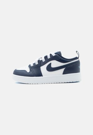 Niskie trampki z białej i granatowej skóry z białymi sznurowadłami i białą gumową podeszwą, logo Nike z boku.