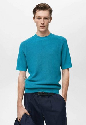 Maglione a maniche corte e scollo rotondo in un vivace colore turchese. Presenta un design pulito e un tessuto testurizzato. Abbinato a pantaloni scuri.