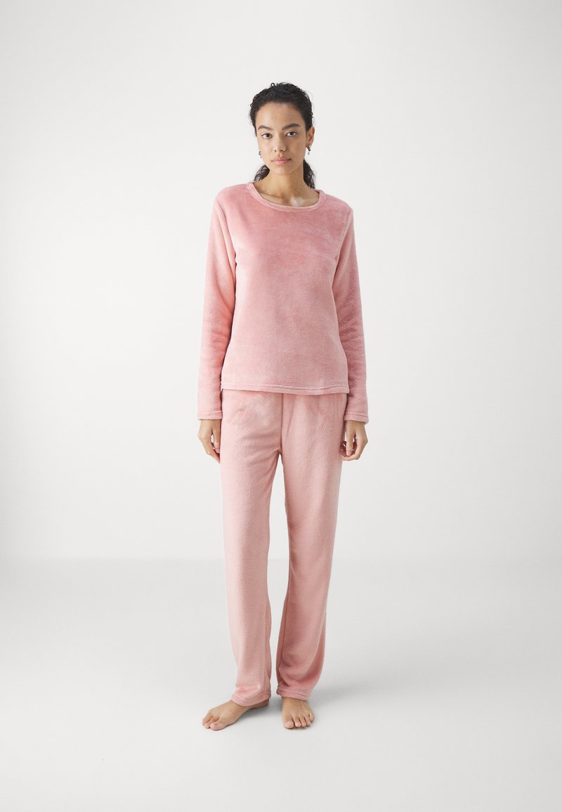 Conjunto de loungewear de forro polar rosa que incluye una camiseta de manga larga con cuello redondo y pantalones a juego. Textura suave, corte relajado, sin patrones.