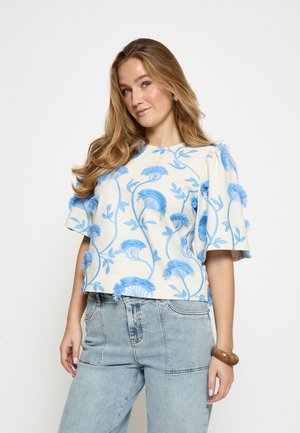 Top s krátkym rukávom z bielej látky s modrou kvetinovou výšivkou, s okrúhlym výstrihom a textúrovanými detailmi na rukávoch.