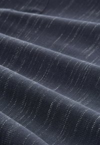 Strukturalna, ciemnogranatowa tkanina z delikatnymi srebrnymi włóknami tworzącymi falisty wzór, z elastycznym splotem wprowadzającym dodatkową głębię.