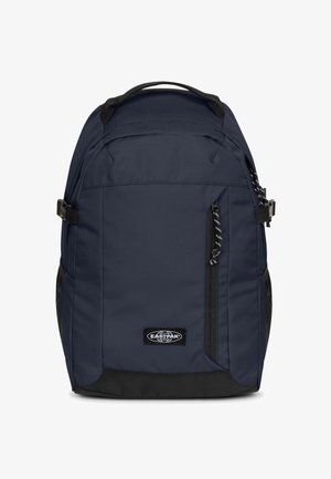 Granatowy plecak z teksturowaną tkaniną, czarnymi akcentami, wieloma kieszeniami na zamek i regulowanymi paskami. Na przedniej stronie znajduje się logo marki.