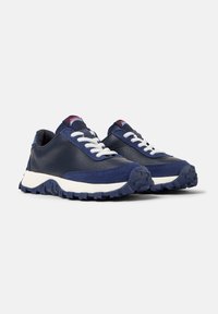 Sneakers blu navy con lacci bianchi e suole texturizzate, caratterizzati da un design sportivo e un branding sottile sulla linguetta.