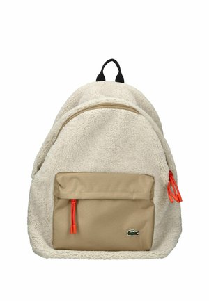 Mochila beige con exterior de forro polar, dos compartimentos con cremallera, cordones naranjas y un pequeño parche de logo verde en el bolsillo frontal.