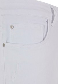 Vaqueros de mezclilla blanca con un bolsillo trasero que tiene un botón de metal plateado y ligeras desgastadas cerca del área del bolsillo. Tejido de textura suave.