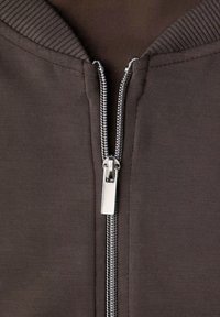 Braune Fleecejacke mit durchgehendem Reißverschluss, Rippkragen und glatter Textur. Der Reißverschluss ist metallisch und verläuft mittig vorne.