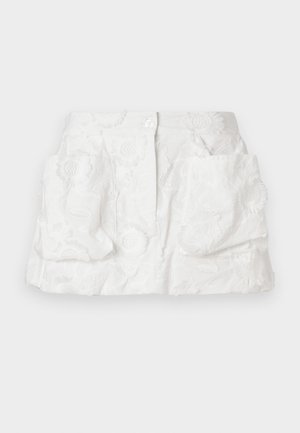 Gonna bianca ricamata con chiusura a bottoni, caratterizzata da motivi floreali e due grandi tasche frontali, realizzata in tessuto leggero.